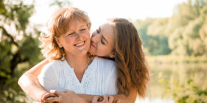 Mature Mother Hugging With Her Teen Daughter outdoor in Nature